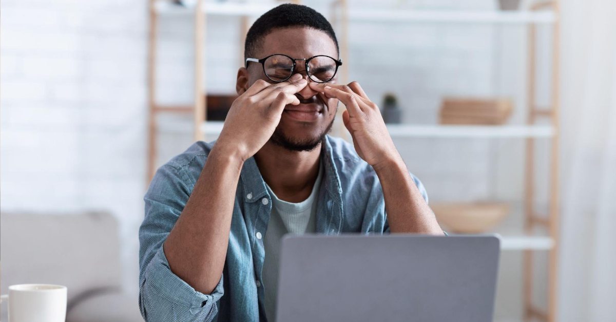 Man sitting at desk rubbing his eyes