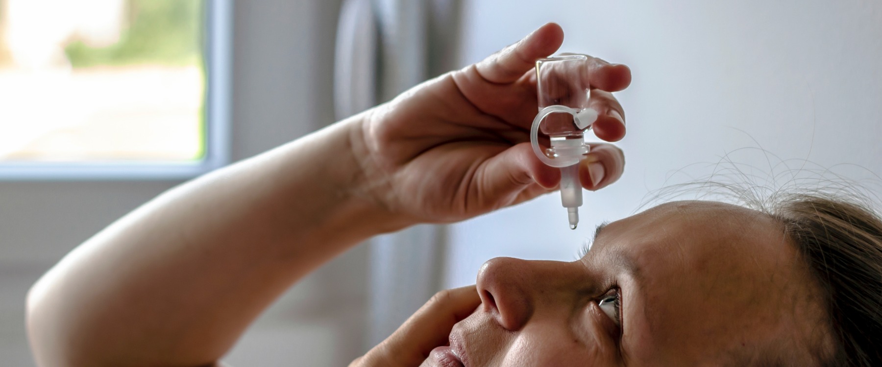 Woman adding eyedrops to eye