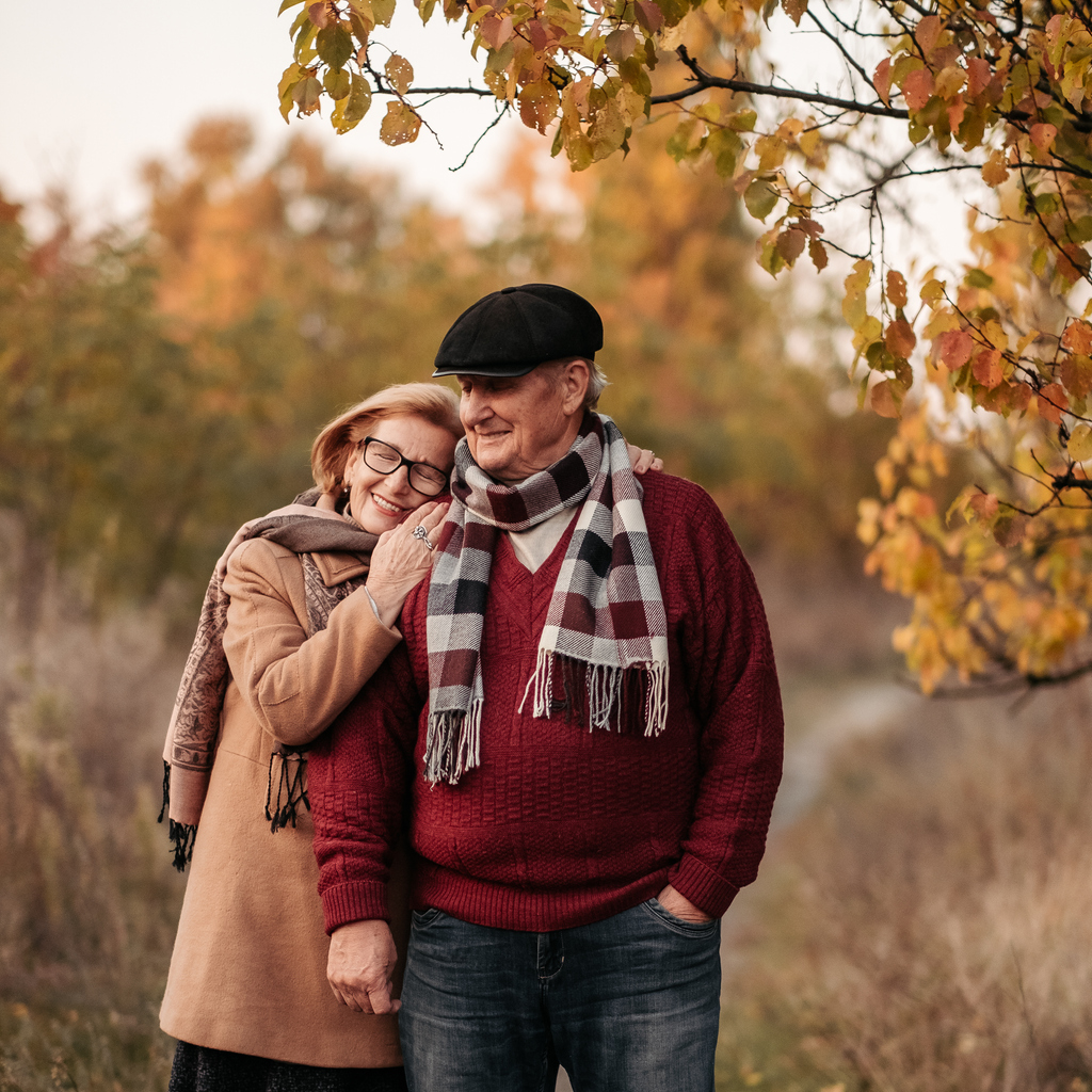 Elderly man looking at his elegant retired woman with love, warming her hands and enjoying her beauty, senior married couple dancing in autumn park, celebrating anniversary, affection