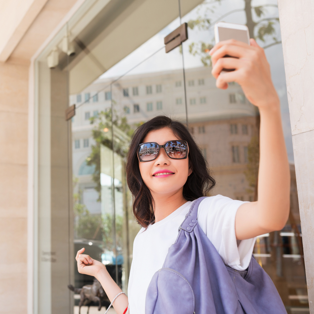 Smiling girl in sunglasses taking selfie