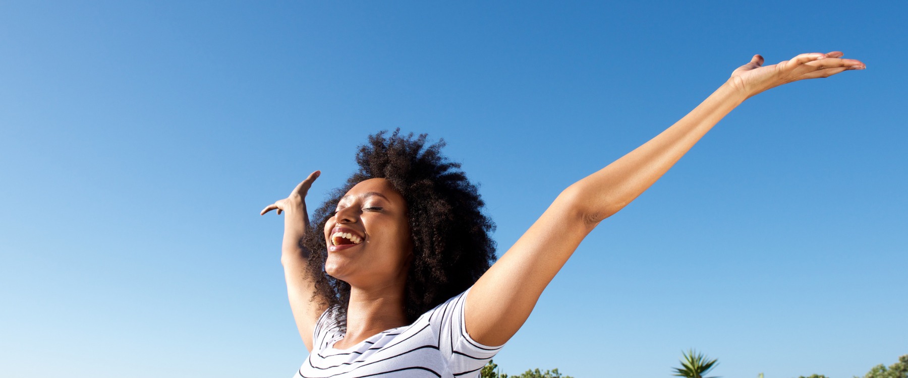 African woman with arms in the air smiling