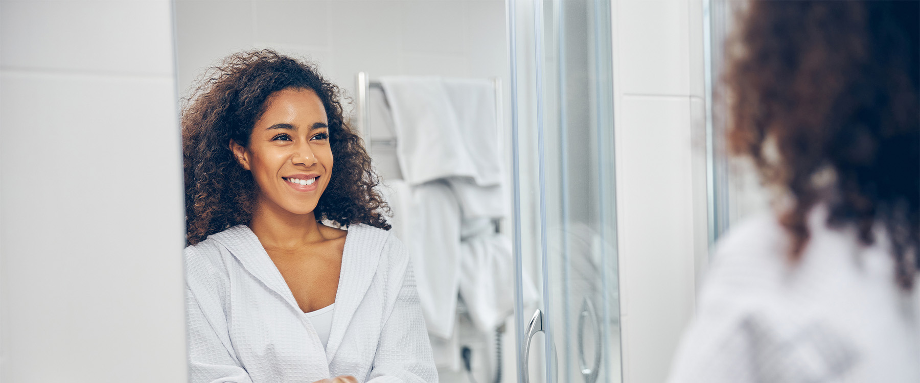 An ocuplastics patient smiling at herself in the mirror.